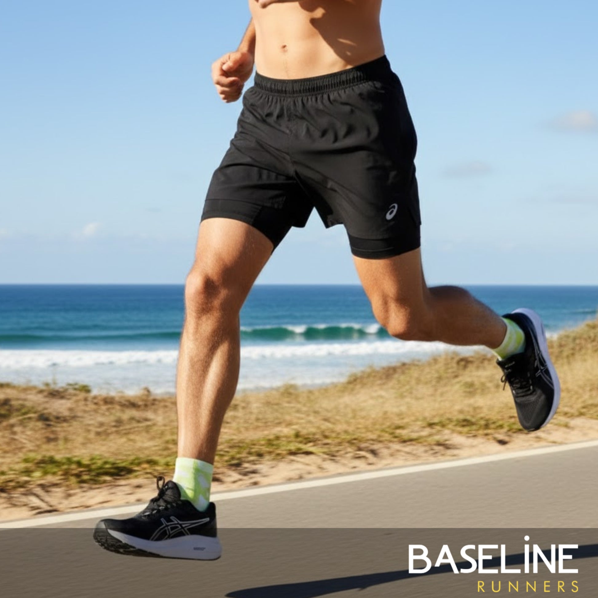 Person running on a road with ocean view wearing black shorts and shoes, with 'Baseline Runners' branding.