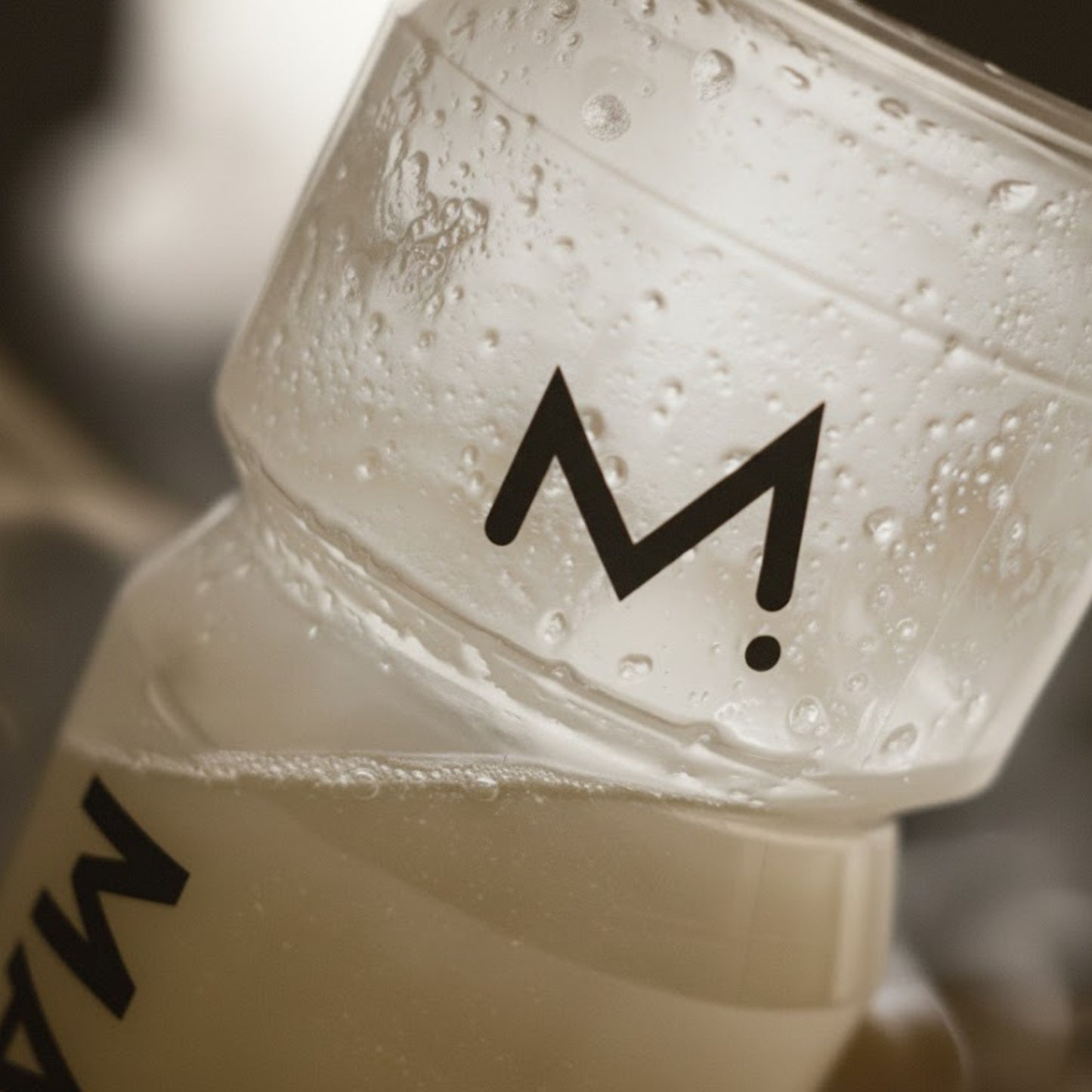 Close-up of a white container with water droplets and a black logo on a blurred background