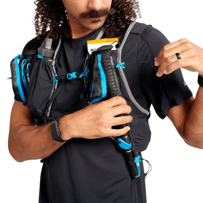 Person wearing a black athletic outfit with a hydration vest and backpack on a white background