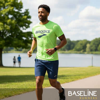 Man running outdoors wearing a Brooks shirt with a lake and trees in the background