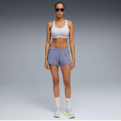 Woman wearing a white Puma sports bra and gray shorts on a white background
