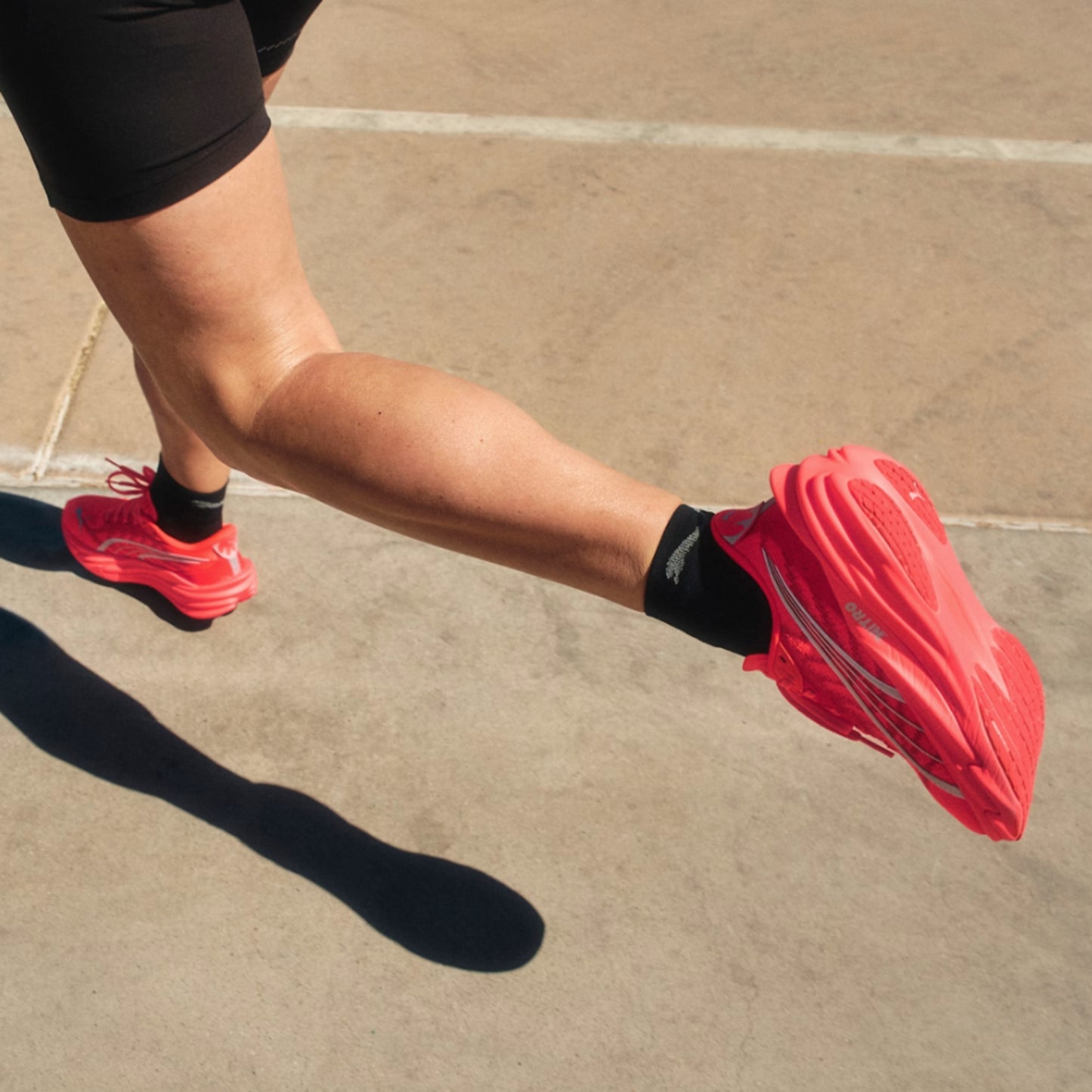 Person running on a paved surface wearing red running shoes and black socks.