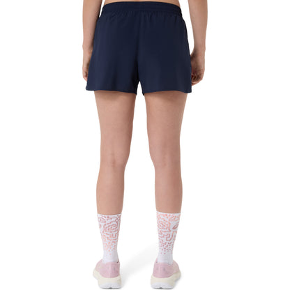 Person wearing navy Asics shorts and white socks with pink accents on a white background