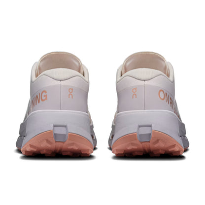 A pair of On Running trail shoes shown from the rear, featuring a light gray and off-white upper with peach-colored midsoles and outsoles, and the On logo visible.
