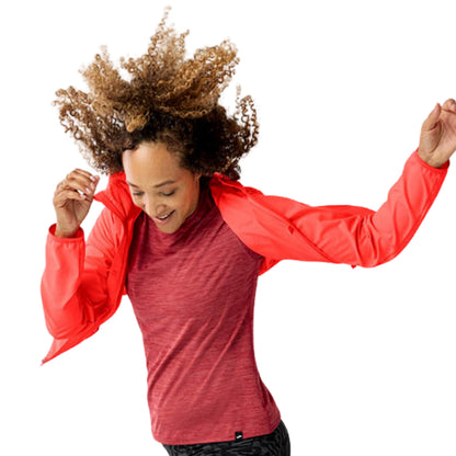 Woman wearing a orange jacket with a Brooks logo on a white background