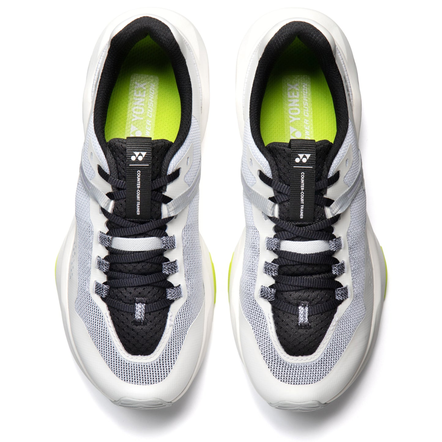 Pair of white and black Yonex running shoes with green accents on a white background