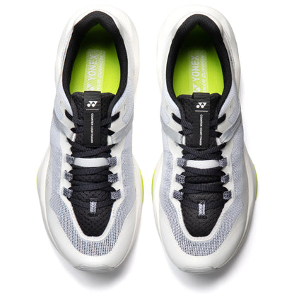 Pair of white and black Yonex running shoes with green accents on a white background