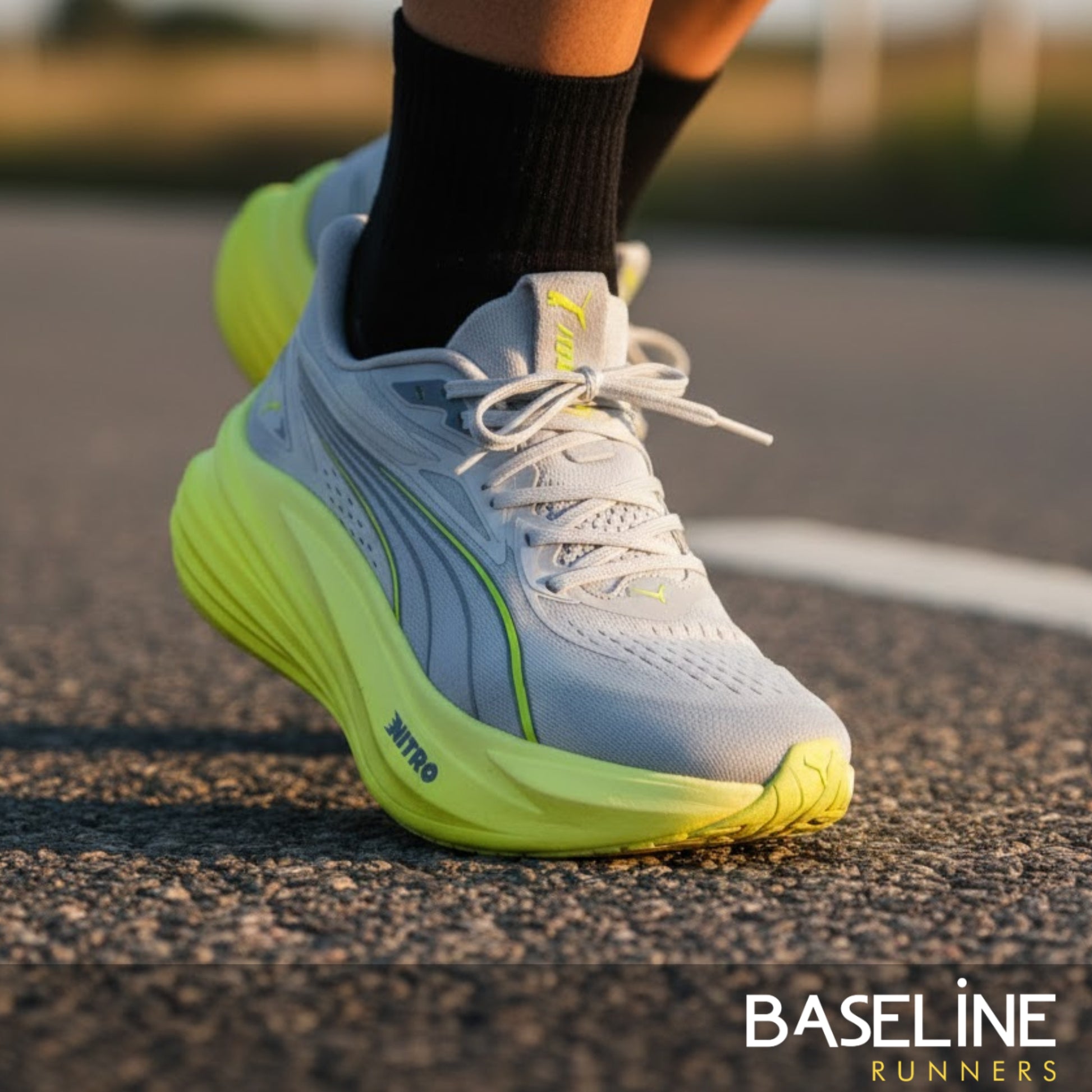Gray and yellow Puma running shoe on a road with 'Baseline Runners' branding.