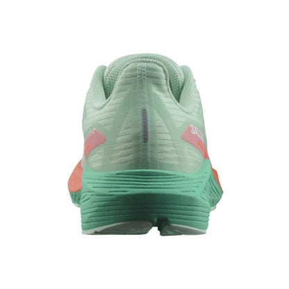 Green running shoe with pink accents on a white background