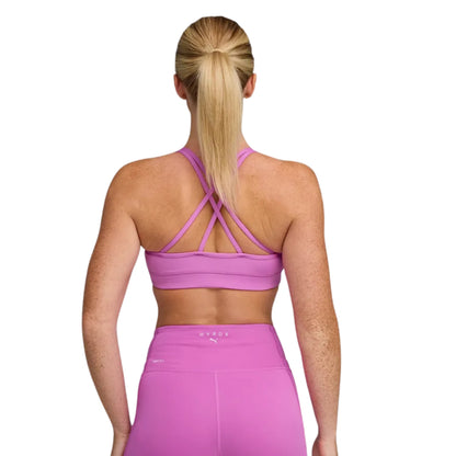 Woman wearing a Strappy Puma Hyrox Bra in colour electric orchid on a white background