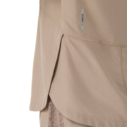 Close-up of a beige athletic top showing the side seam, hem, and a small vertical 'ACTIBREEZE' label on the chest, with a mesh layer visible underneath.