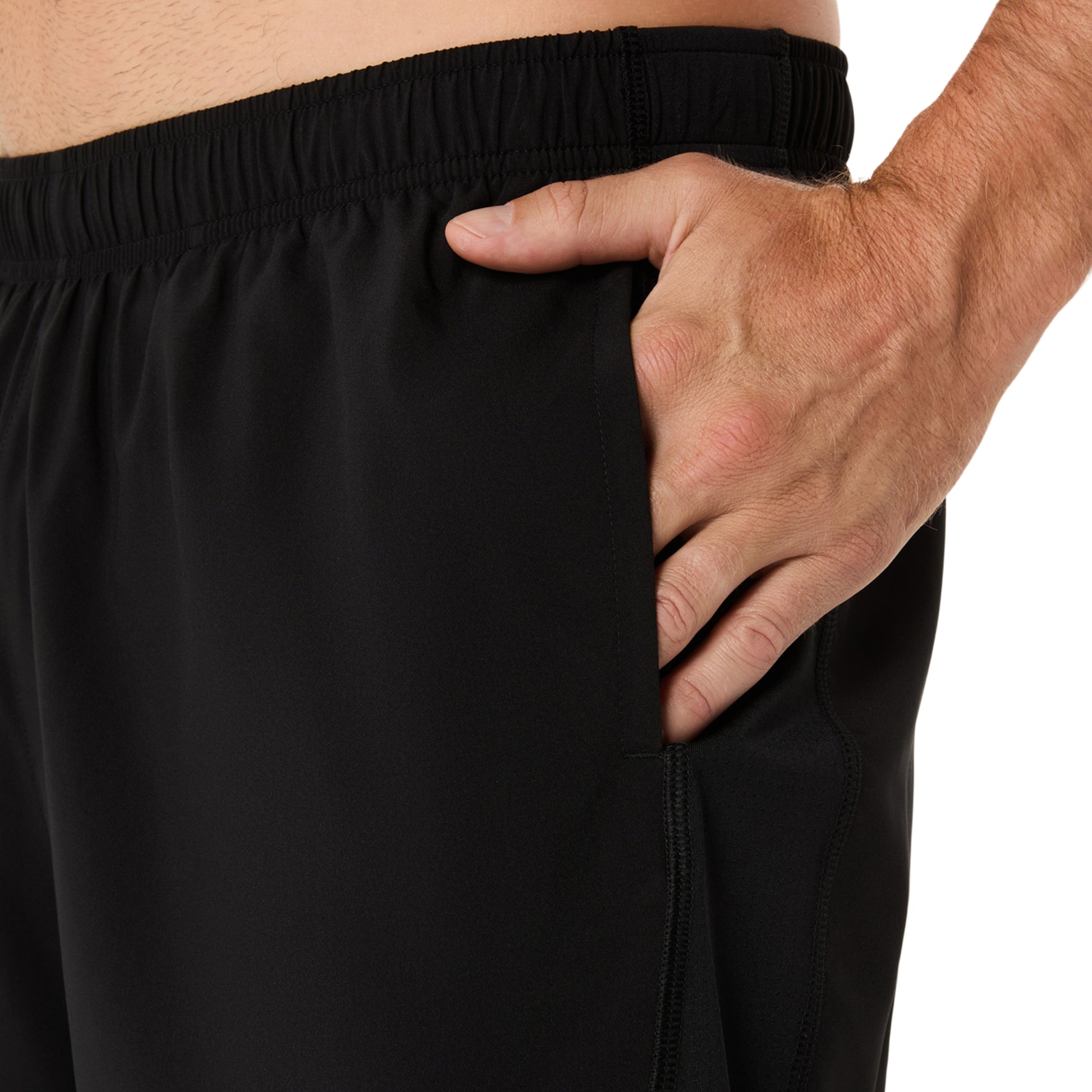 Person wearing black running shorts with a hand in the pocket on a white background