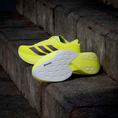 Bright yellow adidas running shoes with white soles on a stone step