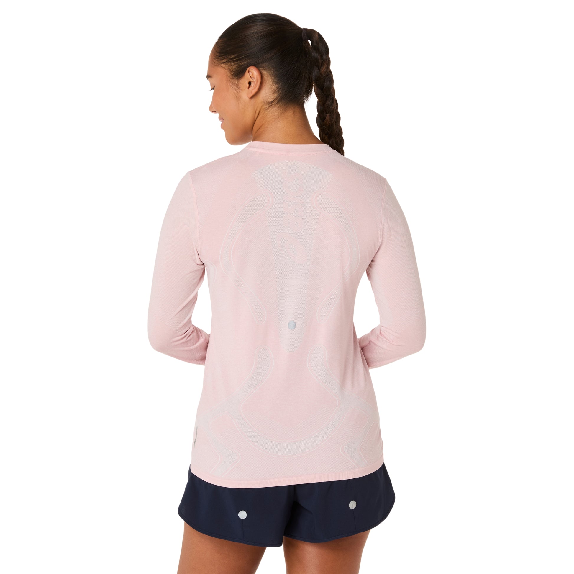 Woman wearing a pink long-sleeve shirt and navy shorts on a white background