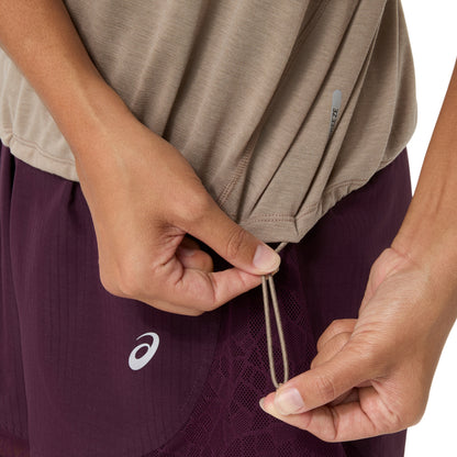 Close-up of a person wearing athletic shorts in deep purple with a white Asics logo, pulling the drawstring of a taupe-brown athletic top.