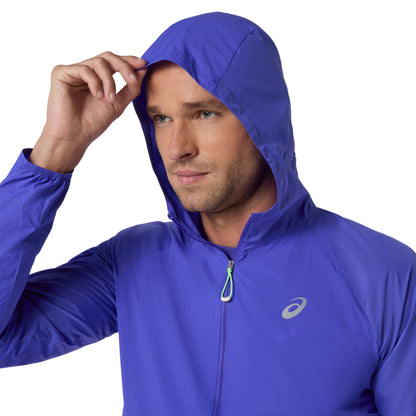 Person wearing blue Asics running jacket, with the hood on a white background