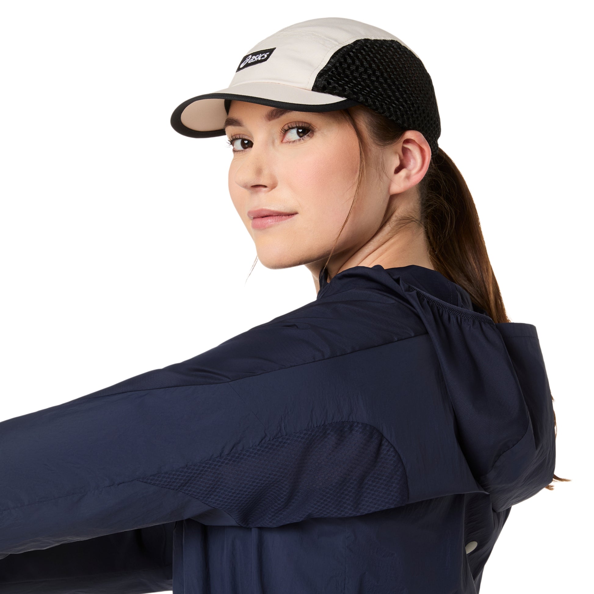 Woman wearing a navy jacket and a white and black cap on a white background