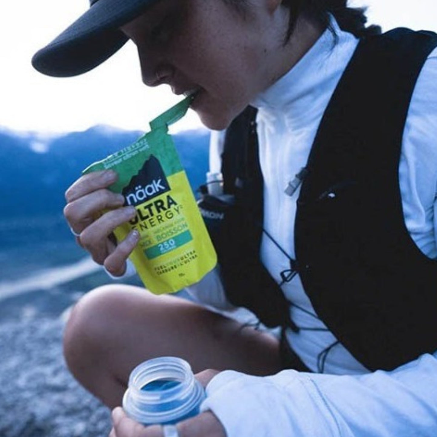 Person outdoors drinking from a Naak Ultra Energy drink package