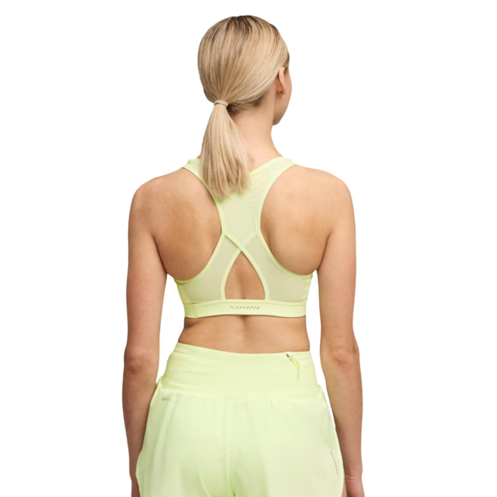 Woman wearing a light green sports Puma bra and leggings on a white background
