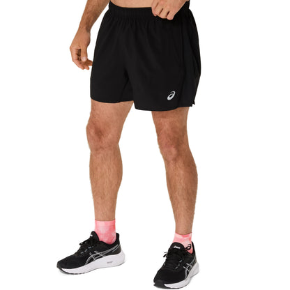 Person wearing black athletic shorts and black sneakers on a white background