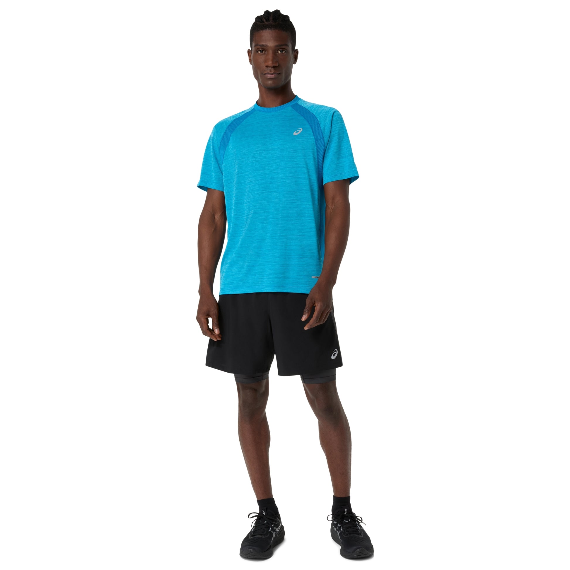 Man wearing a blue Asics shirt and black shorts on a white background