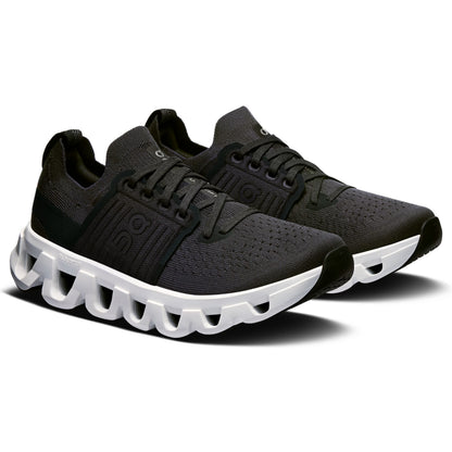A pair of black On running shoes with a distinctive white sculpted sole, displayed on a clean white background.