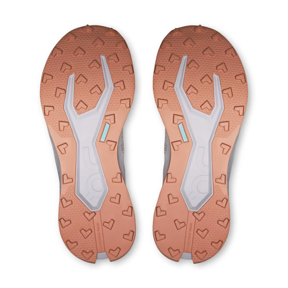 Top-down view of a pair of On shoes shoes showing the textured outsoles in a warm copper-orange color with white and gray central support structures and a small light blue accent.