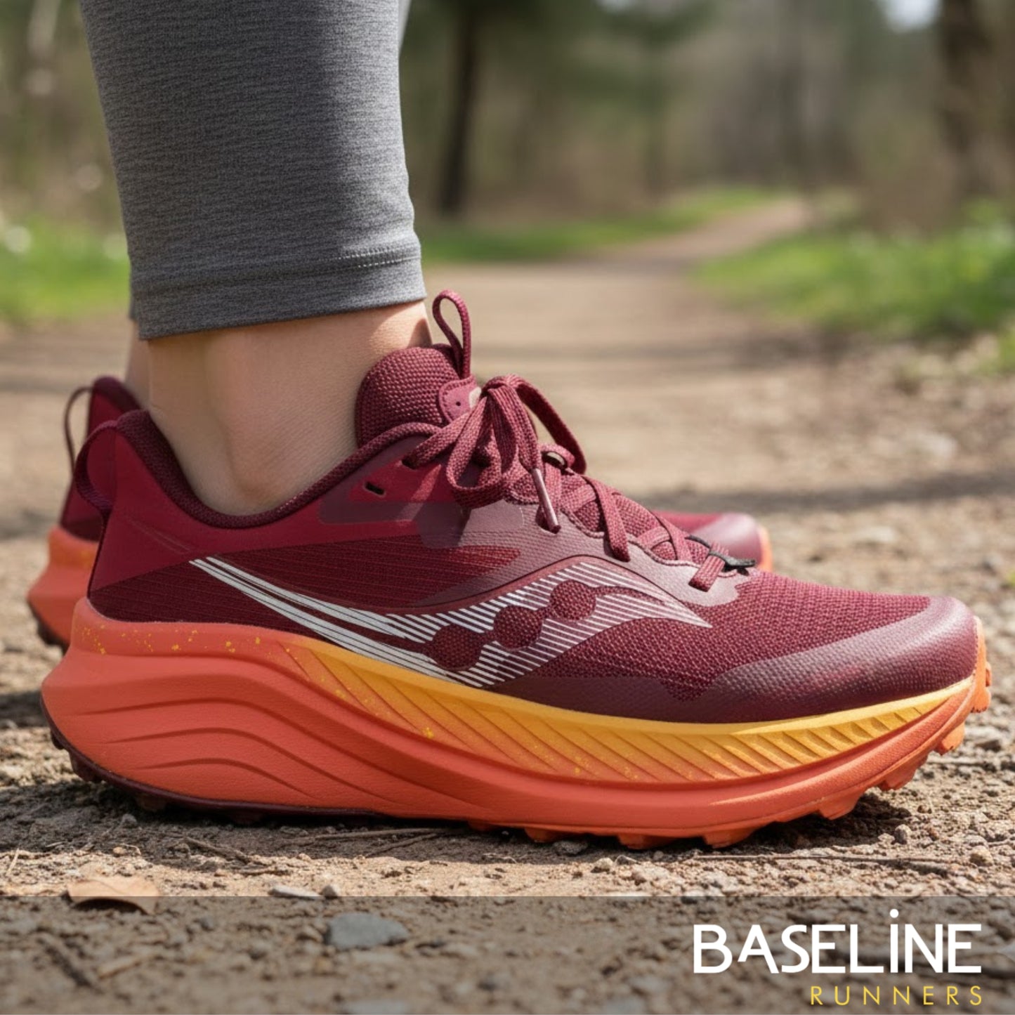 Maroon and orange running shoes on a person's foot with a blurred natural background