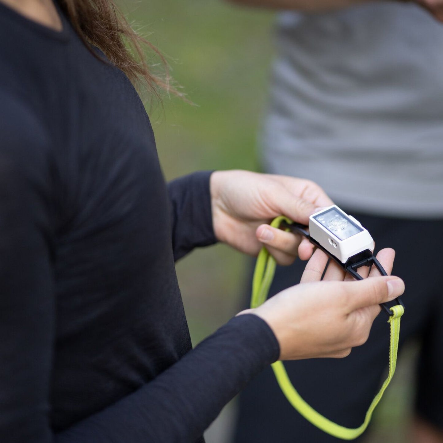 Person holding a headlamp with a green cable outdoors