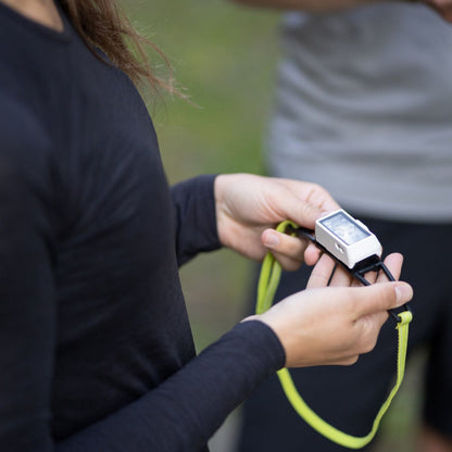 Person holding a headlamp with a green cable outdoors
