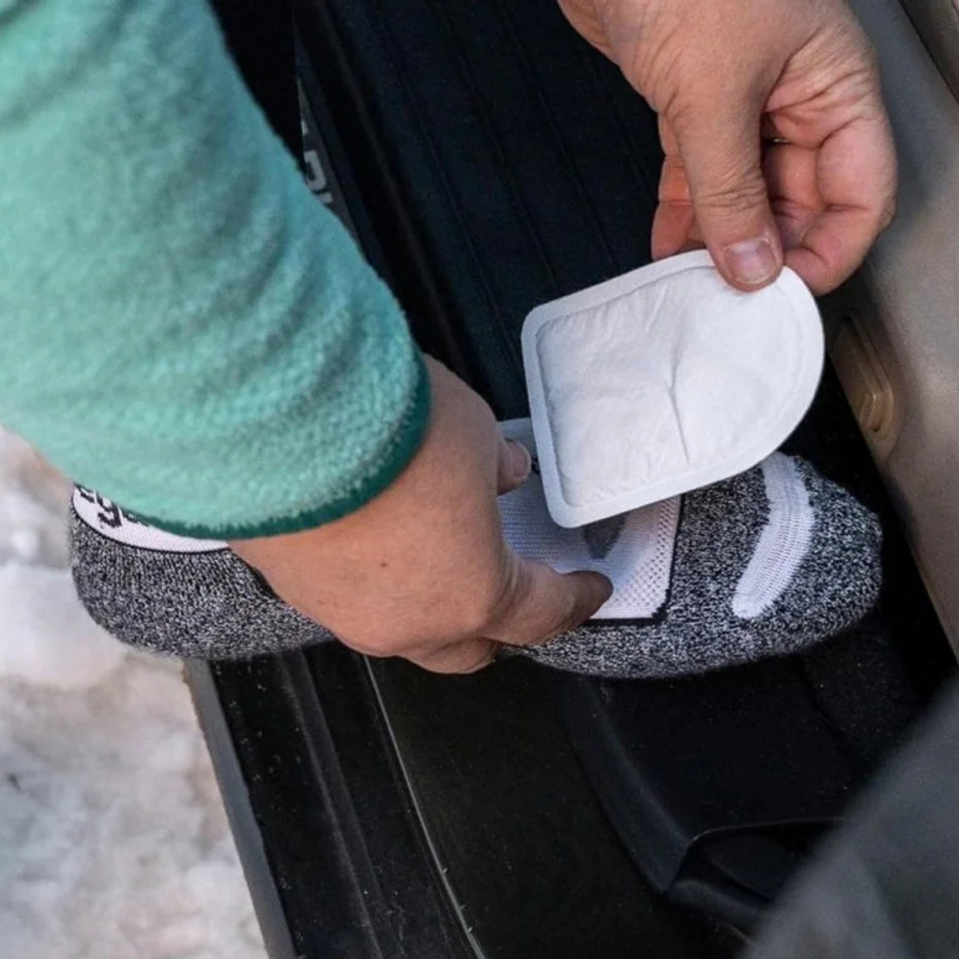 Person holding a white rectangular object with a textured surface, possibly a filter or a small device, against a blurred background.