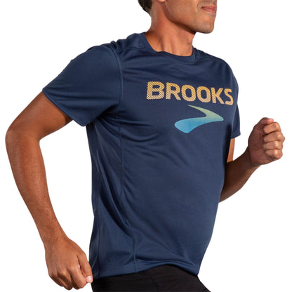 Man wearing a blue Brooks t-shirt on a white background