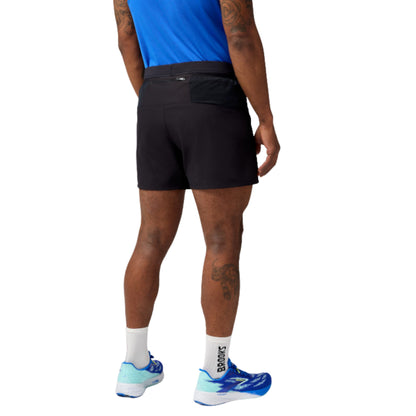 Person wearing black running shorts and blue running shoes on a white background