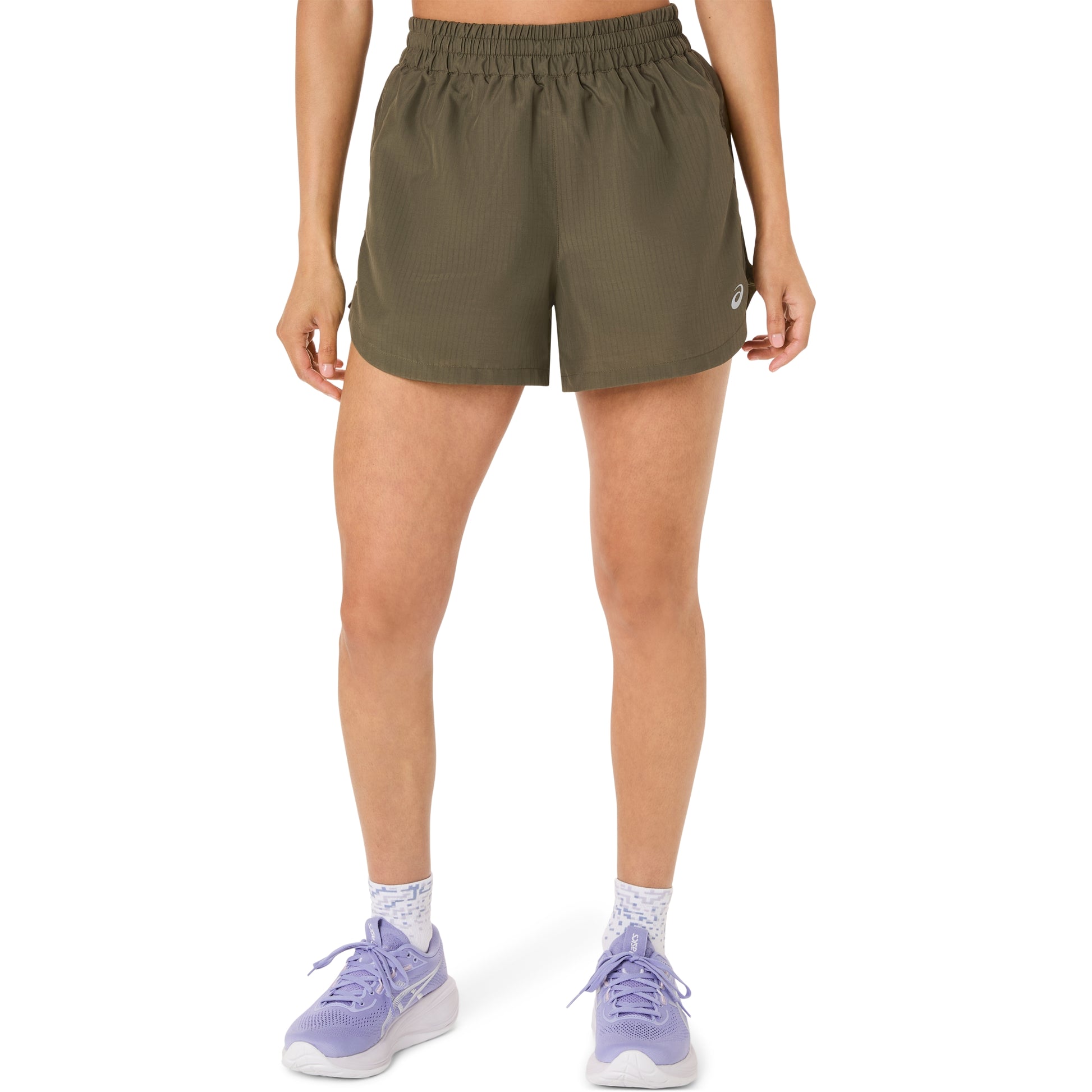 Person wearing olive green Asics shorts on a white background