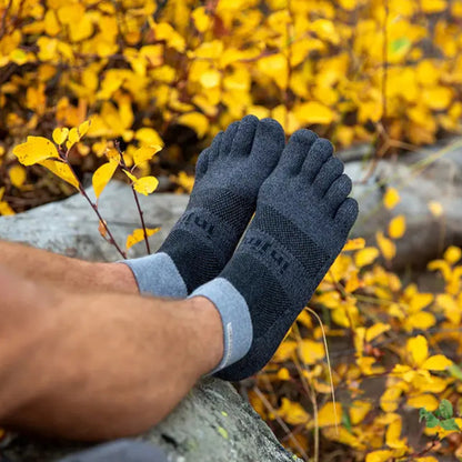 Person wearing toe-separated socks on a rocky surface with blurred natural background