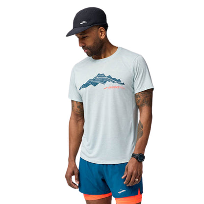 Man wearing a white t-shirt with mountain design and blue shorts on a white background