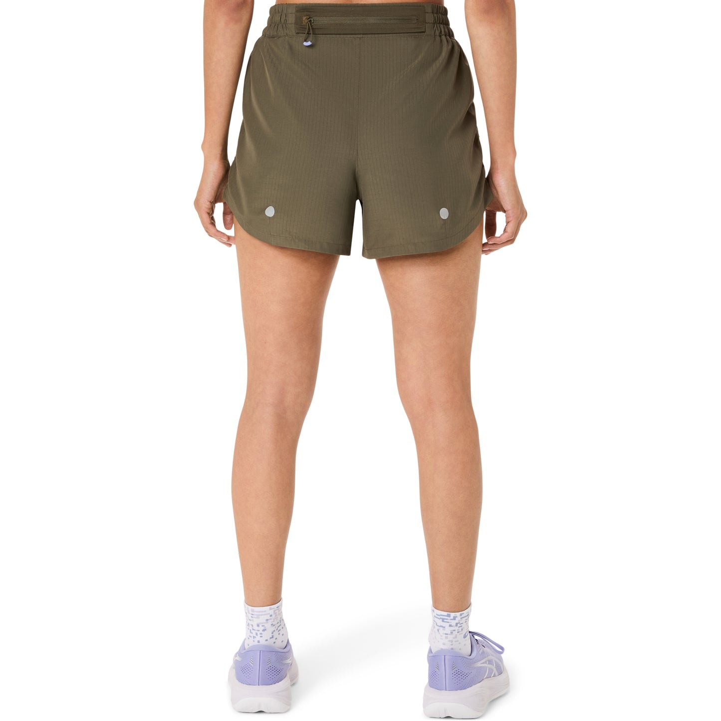 Person wearing olive green Asics shorts on a white background
