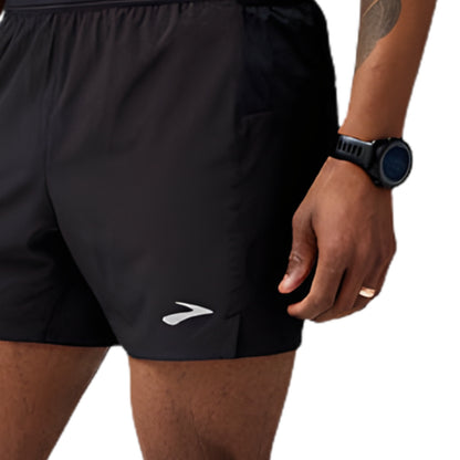 Person wearing black running shorts with a brand logo, holding a smartwatch.