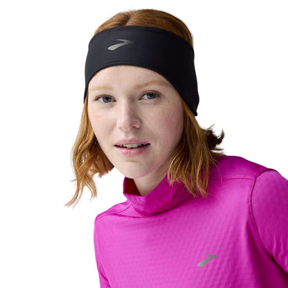 Woman wearing a black Brooks headband on a white background