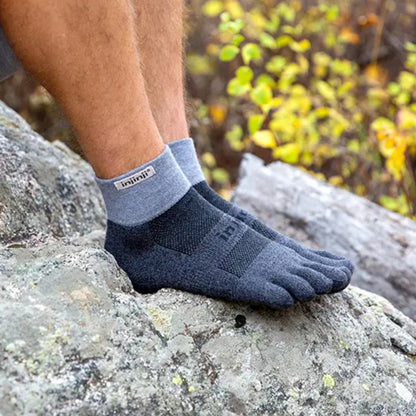Person wearing toe-separated socks on a rocky surface with blurred natural background