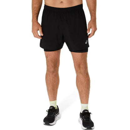 Person wearing black athletic shorts with a logo on a white background