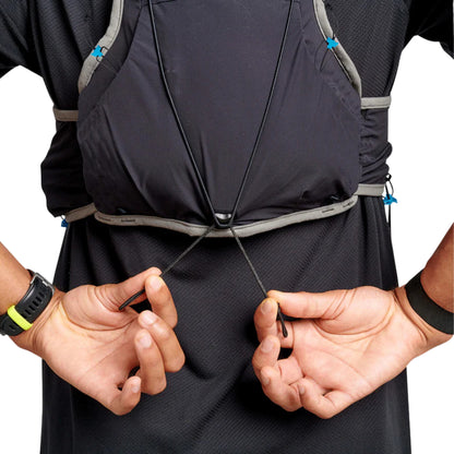 Person adjusting a black hydration vest with visible straps on a white background