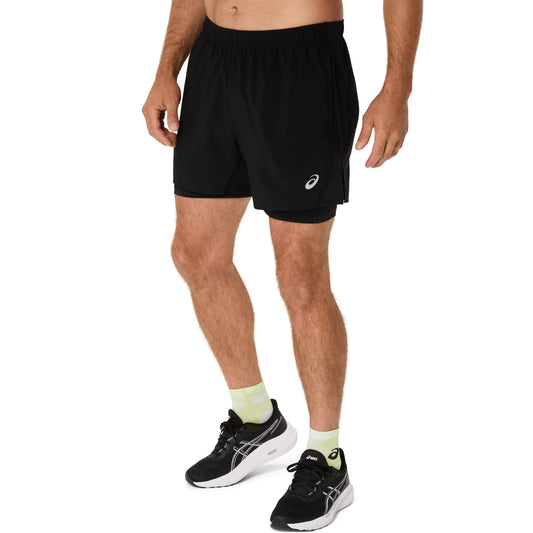 Person wearing black athletic shorts and black running shoes on a white background