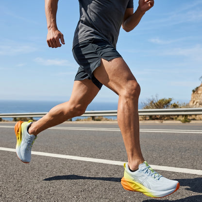 Person running on a road in daylight with Asics running shoes