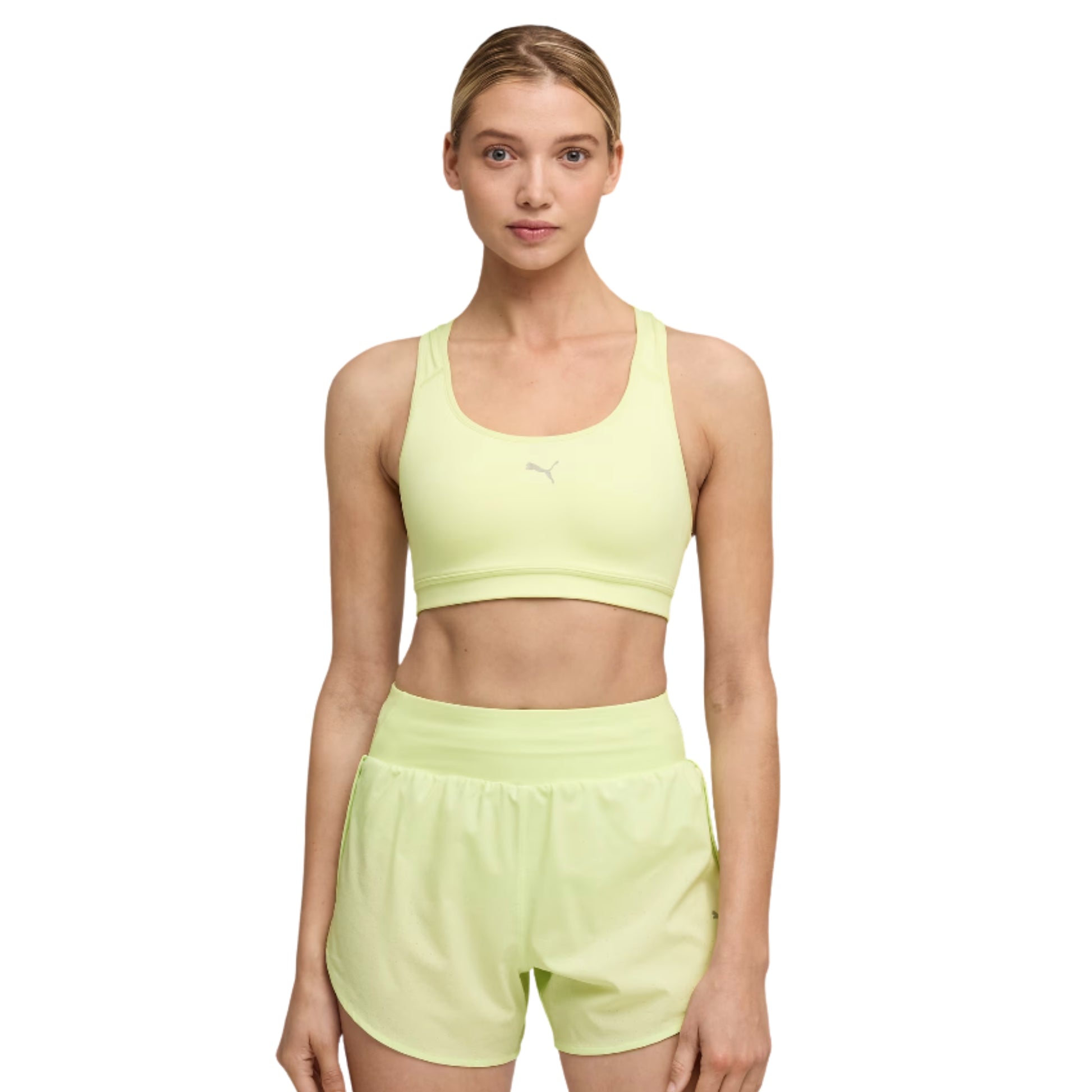 Woman wearing a light green sports Puma bra and shorts set on a white background