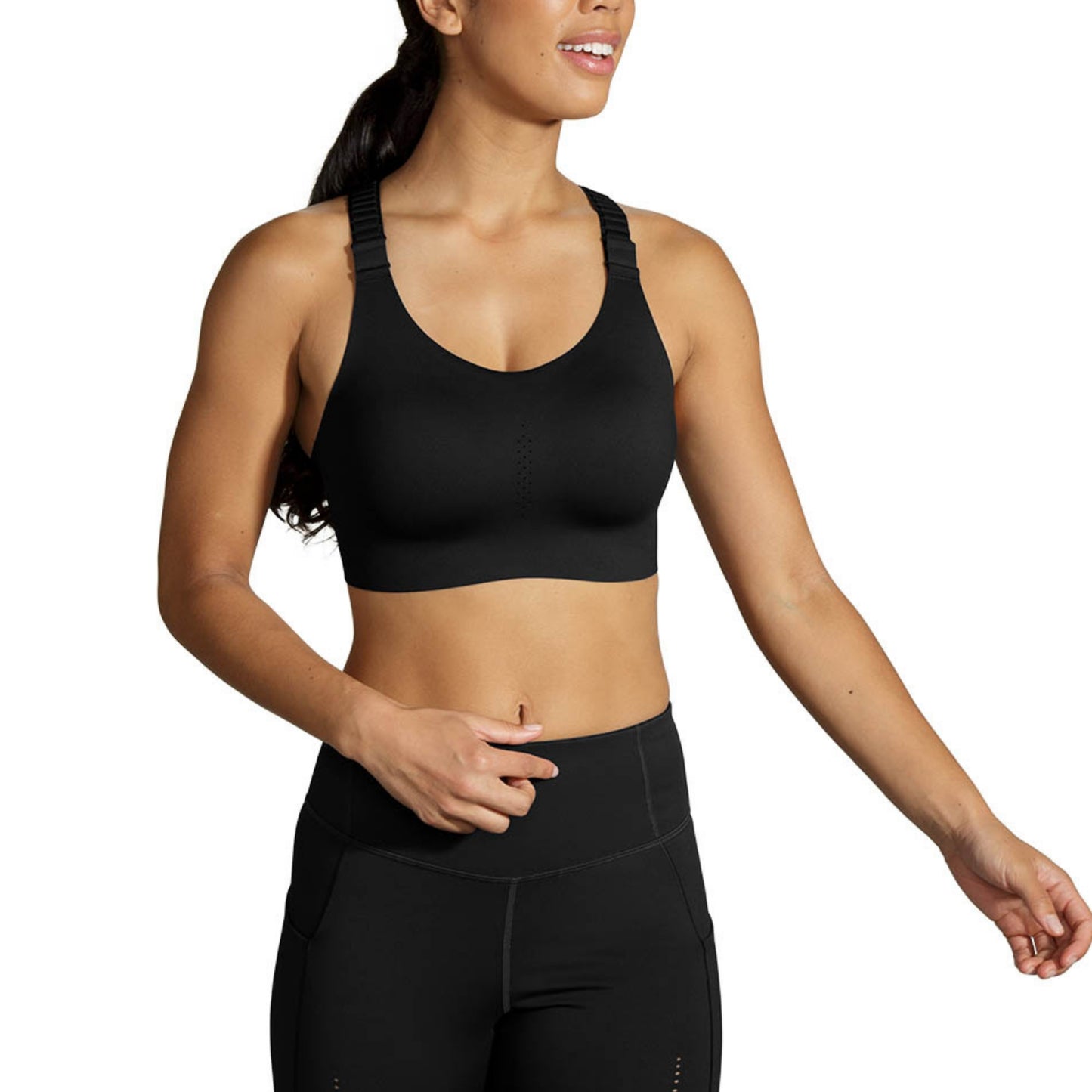 A woman wearing a black sports bra and matching black high-waisted leggings, cropped from the mouth down against a plain white background.