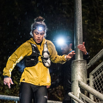 Two people with headlamps navigating a rainy night path.
