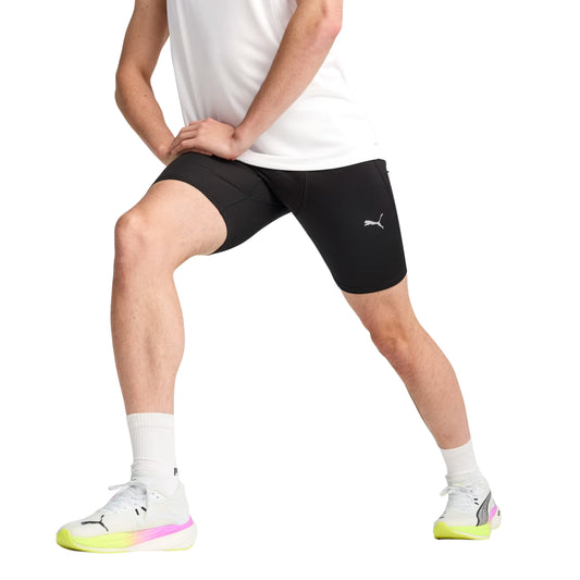 Person wearing black Puma tights with a logo, white socks, and white sneakers on a white background