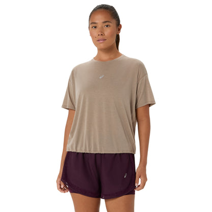 A woman modeling a light taupe short-sleeve athletic t-shirt and dark plum athletic shorts against a plain white background.
