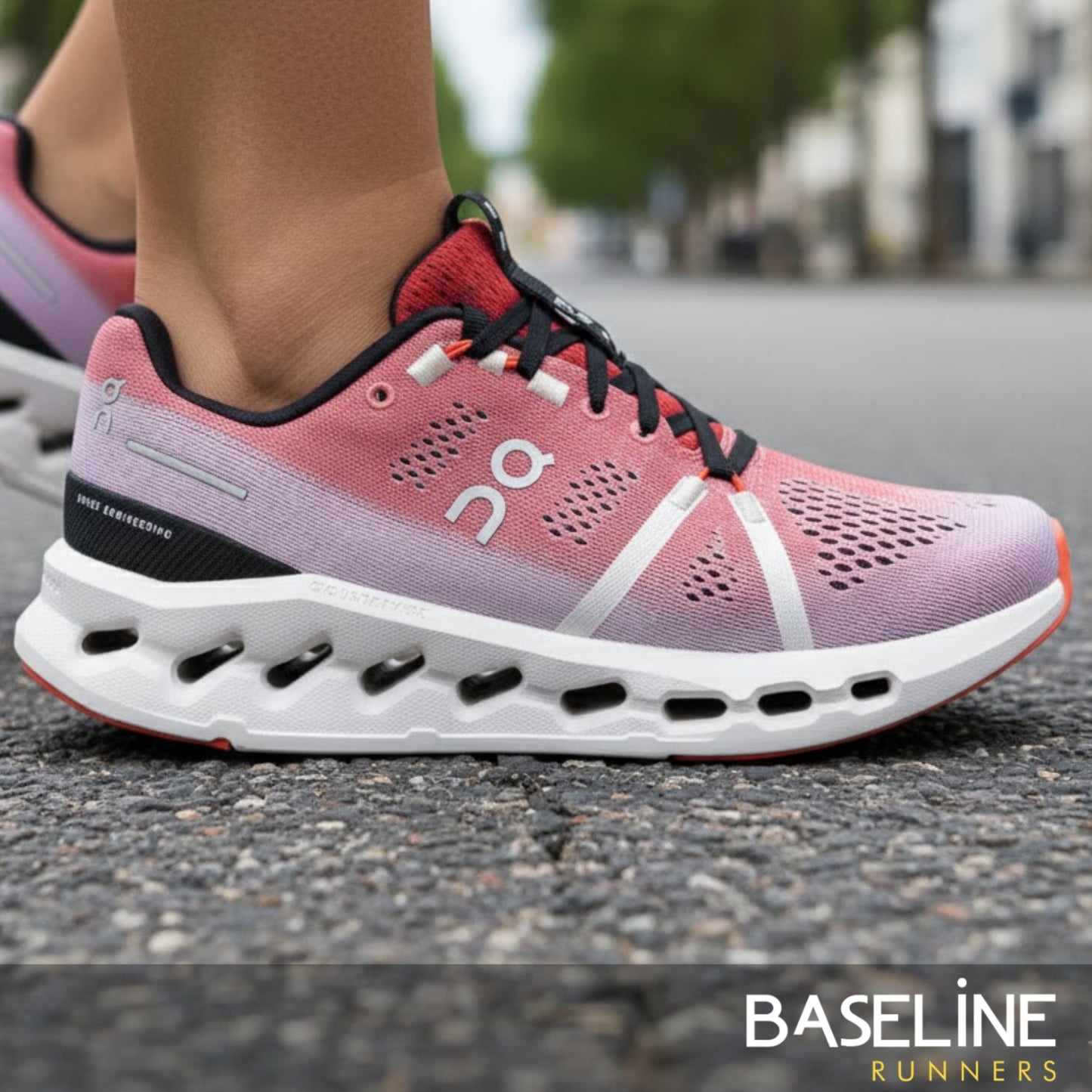 Pink and red running shoe with white sole on a blurred street background